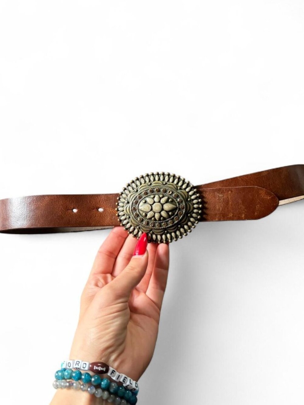 brown leather statement belt featuring an ornate, oversized brass-toned medallio